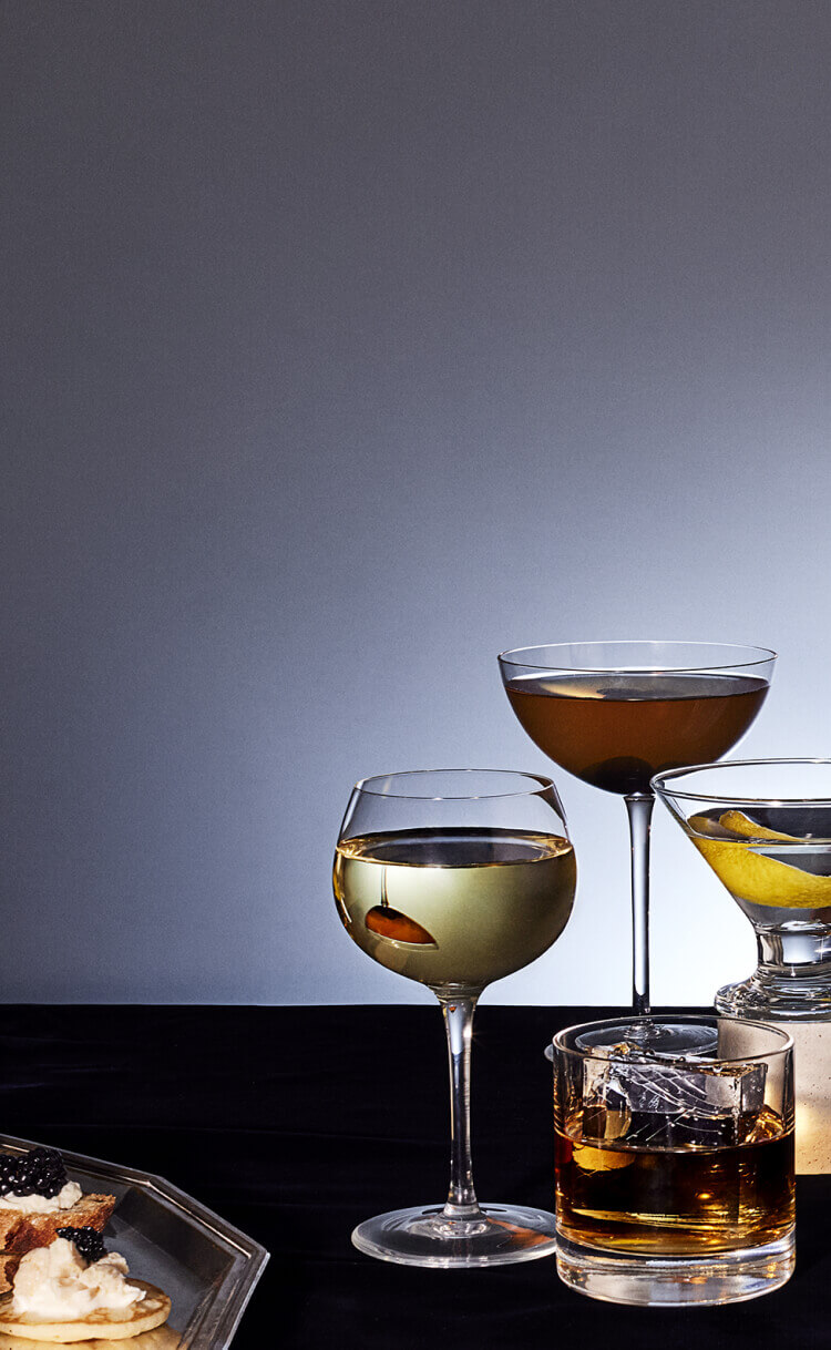 A table of various cocktails over a gray background.