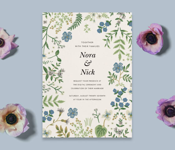 A blue and sage floral invitation propped with 4 purple anemones.