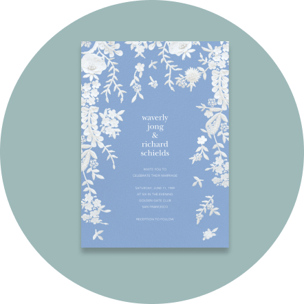 A light-blue wedding invitation with cascades of white flowers dripping from the top.