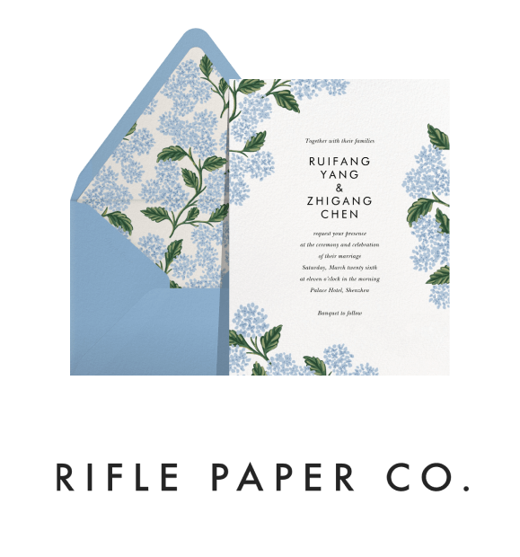 A blue floral Rifle Paper Co. invitation with a matching envelope, and logo.